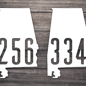 May include: Two white outlines of the state of Alabama with the area codes 256 and 334 printed inside.