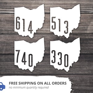 May include: Four white Ohio state outline decals with the area codes 614, 513, 740, and 330 printed in black.