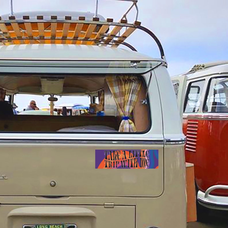 May include: A white vintage van with a wooden roof rack and a colorful sticker on the back that says "Take a little trip with me".