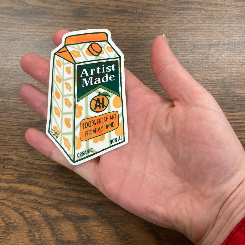 May include: A sticker of a carton of orange juice with the text "Artist Made" and "100% Fresh Art From My Hand". The carton is decorated with a pattern of orange slices and green leaves. The sticker is labeled "Organic" and "Non AI".