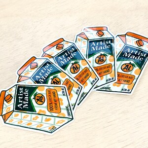 May include: Five stickers with a juice box design. The stickers are white with green and orange accents. The text on the stickers reads "Artist Made" and "100% Fresh Art From My Hand".
