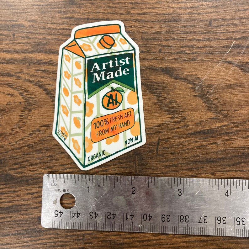 May include: A sticker of a carton of orange juice with the words "Artist Made" and "100% Fresh Art From My Hand" on it. The carton is green, orange, and white with a stylized orange on the front.
