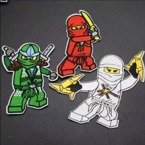 Könnte beinhalten: Drei gestickte Aufnäher mit Ninja-Charakteren in Rot, Grün und Weiß. Jeder Ninja befindet sich in einer Kampfhaltung und hält Waffen wie Schwerter und Wurfsterne. Die Aufnäher haben einen schwarzen Rand und sind auf dunklem Hintergrund.