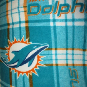 Może przedstawiać: Tkanina w kratę w kolorze turkusowym i białym z napisem "Miami Dolphins" w kolorze pomarańczowym i logo Miami Dolphins, przedstawiającym delfina wyskakującego z słońca, w środku.