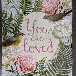 May include: Fabric panel with a floral and bird design. The panel features pink peonies, white hydrangeas, and green ferns surrounding a central circle with the words "You are loved" in pink script. Two birds are perched among the flowers.