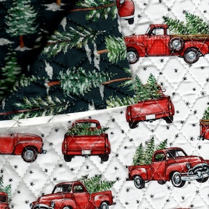 May include: Quilted fabric featuring a repeating pattern of red vintage pickup trucks carrying Christmas trees on a white background with black star accents. A separate section displays a dark green fabric with a pine tree design.
