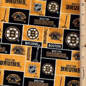 Pode incluir: Tecido com um padrão repetido do logotipo do Boston Bruins, o nome da equipa e tacos de hóquei em preto, dourado e branco. Inclui o logótipo da NHL e um logótipo do urso Bruins.