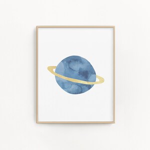 May include: A watercolor painting of a blue planet with a gold ring around it. The planet is surrounded by a white background.