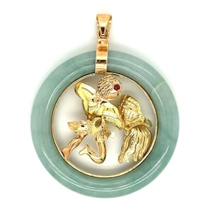 May include: A gold pendant featuring the astrological sign Aquarius, set in a jade circle. The pendant is detailed with a gold figure of a man pouring water from a jar, with a red gemstone for an eye.
