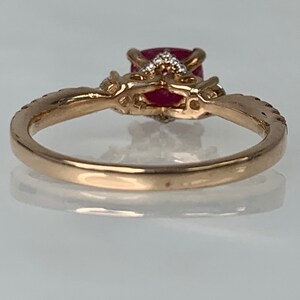 Puede incluir: Un anillo de oro con una piedra preciosa roja y piedras blancas m&aacute;s peque&ntilde;as engastadas en un dise&ntilde;o delicado.