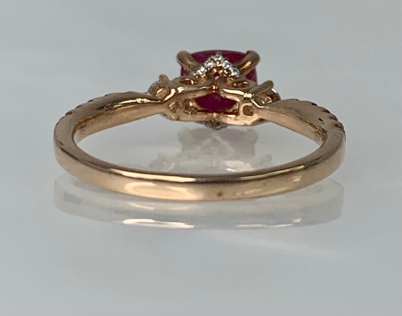 Puede incluir: Un anillo de oro con una piedra preciosa roja y piedras blancas m&aacute;s peque&ntilde;as engastadas en un dise&ntilde;o delicado.