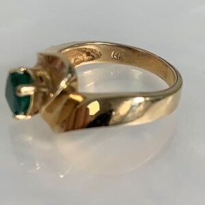Peut inclure: Une bague en or avec une pierre pr&eacute;cieuse verte sertie dans une bande torsad&eacute;e. La bague est marqu&eacute;e "14K" &agrave; l'int&eacute;rieur.