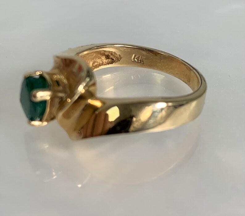 Peut inclure: Une bague en or avec une pierre pr&eacute;cieuse verte sertie dans une bande torsad&eacute;e. La bague est marqu&eacute;e "14K" &agrave; l'int&eacute;rieur.