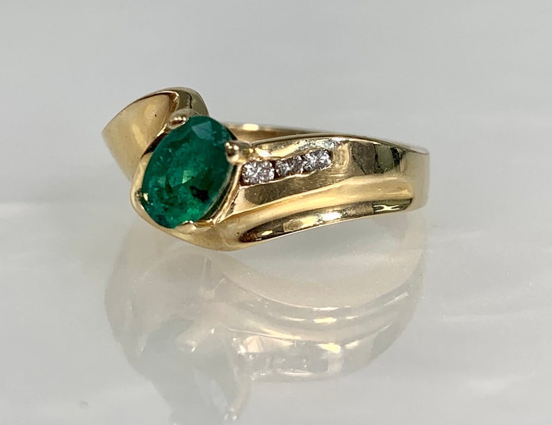Peut inclure: Une bague en or avec une grande &eacute;meraude ovale et une rang&eacute;e de petits diamants sertis dans la bande.