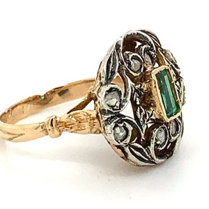 May include: A gold and silver ring with a green emerald gemstone and small diamonds set in a floral design.