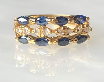 May include: A gold band ring with three rows of marquise-shaped blue sapphires and round white diamonds.