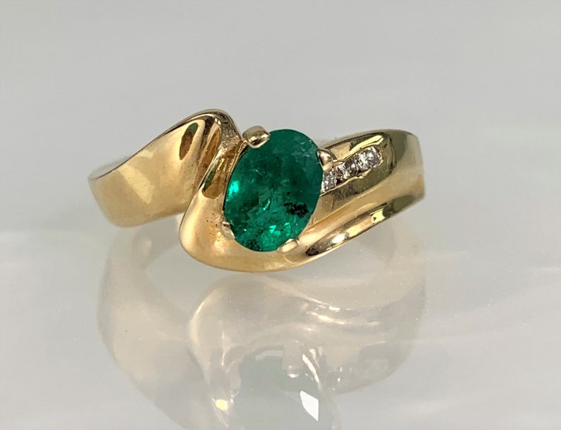 Peut inclure: Une bague en or avec une &eacute;meraude verte et de petits diamants sertis dans la bande.