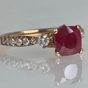 Puede incluir: Un anillo de oro rosa con una gran piedra preciosa de rub&iacute; rojo y diamantes m&aacute;s peque&ntilde;os engastados en la banda.
