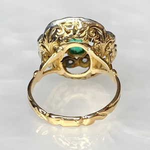 May include: A gold ring with a green gemstone set in a filigree design. The ring has a twisted band.