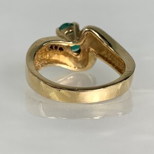 Peut inclure: Une bague en or avec une pierre pr&eacute;cieuse verte sertie dans une bande torsad&eacute;e. La bague est sertie de pierres pr&eacute;cieuses plus petites sur la bande.