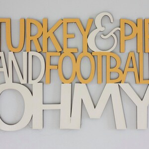 May include: A wooden sign with the words "TURKEY & PIE AND FOOTBALL OH MY" in white and yellow letters.