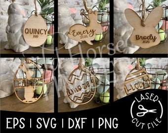 May include: Set of six laser cut wooden Easter egg decorations featuring bunny and egg designs. The ornaments are personalised with names and the year 2020. The ornaments are displayed on a table with a basket of Easter eggs.