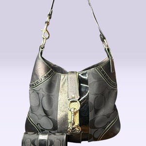 May include: Black shoulder bag and matching wallet set. The bag features a repeating pattern and a silver-tone clasp. The wallet has a matching pattern and a black strap closure. Both items have white stitching.