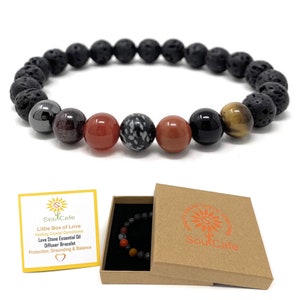 May include: A black lava stone diffuser bracelet with carnelian, hematite, black onyx, tiger's eye, and snowflake obsidian beads. The bracelet comes in a small cardboard box with the SoulCafe logo. "Little Box of Love" Healing Crystal Gemstones Lava Stone Essential Oil Diffuser Bracelet Protection, Grounding & Balance.