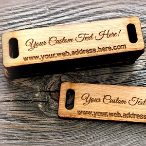 May include: Two wooden tags with rounded corners and a hole in the centre. The tags are engraved with the text "Your Custom Text Here!" and "www.your.web.address.here.com".
