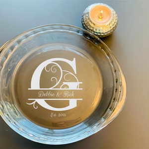 May include: A clear glass pie plate with a white etched design featuring a large letter "G" with swirls and the text "Debbie & Rick Est. 2016".