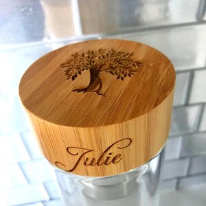 May include: A glass jar with a bamboo lid. The lid has a tree design and the name "Julie" engraved on it.