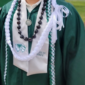 May include: A green graduation gown with a white and green lei, a black beaded necklace with a silver medallion, and a white sash with the text "College of Science".
