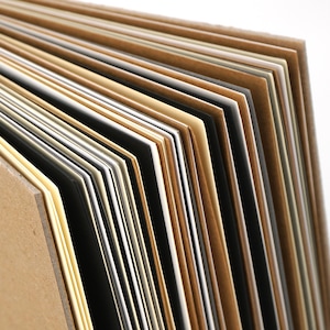May include: A stack of different colored cardstock paper. The paper is arranged in a fan shape, with the top of the stack being the lightest color and the bottom of the stack being the darkest color.