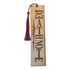 May include: A wooden bookmark with a purple tassel. The bookmark has the words "DEATH NOTE" written on it in a stylized font.