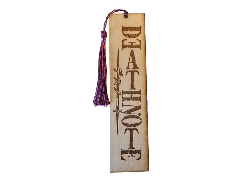May include: A wooden bookmark with a purple tassel. The bookmark has the words "DEATH NOTE" written on it in a stylized font.