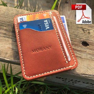 May include: A brown leather cardholder with white stitching and the embossed word "MORANY". The cardholder contains several credit cards and a driver's license. The PDF Adobe logo is in the upper right corner.
