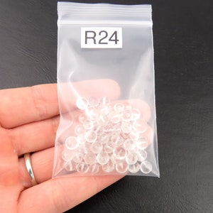 K&ouml;nnte beinhalten: Ein transparenter Plastikbeutel mit einem wei&szlig;en Etikett mit der Aufschrift "R24" enth&auml;lt eine gro&szlig;e Menge kleiner, transparenter, runder Perlen.