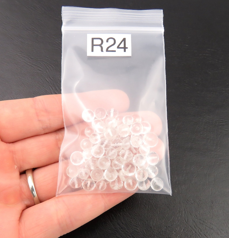 K&ouml;nnte beinhalten: Ein transparenter Plastikbeutel mit einem wei&szlig;en Etikett mit der Aufschrift "R24" enth&auml;lt eine gro&szlig;e Menge kleiner, transparenter, runder Perlen.