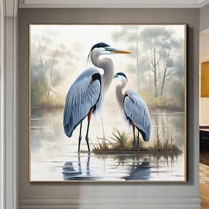 Könnte beinhalten: Gerahmtes Gemälde mit zwei blauen Reihern, die in einem nebligen See stehen. Die Vögel haben lange Beine und Schnäbel, mit einem Hintergrund aus Bäumen und Wasser. Das Kunstwerk wird in einem gut beleuchteten Flur ausgestellt.