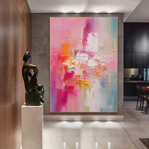 K&ouml;nnte beinhalten: Abstraktes &Ouml;lgem&auml;lde mit einer Farbpalette aus Rosa, Orange, Wei&szlig; und Blau. Das Kunstwerk zeichnet sich durch dicke Pinselstriche und eine strukturierte Oberfl&auml;che aus, die eine moderne und lebendige &Auml;sthetik erzeugt. Das Gem&auml;lde wird in einem Raum mit einer Skulptur ausgestellt.