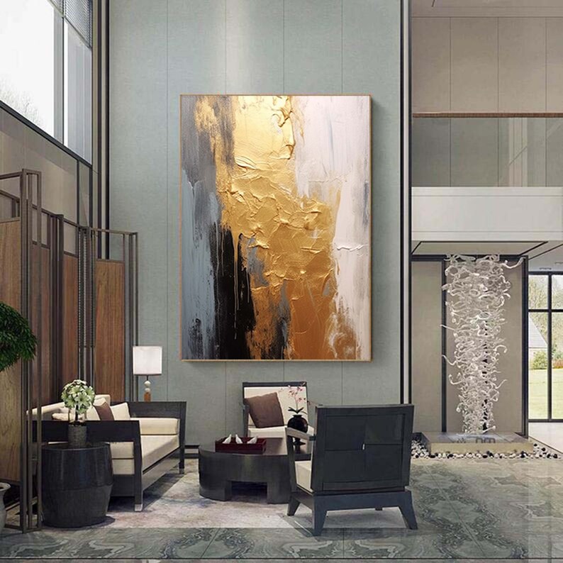 Puede incluir: Pintura abstracta con pintura dorada, negra y blanca. La pintura est&aacute; colgada en una pared de una sala de estar moderna.