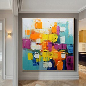 May include: Abstract painting with bold, colorful blocks of yellow, orange, purple, blue, and white paint. The painting has a textured, brushstroke effect.