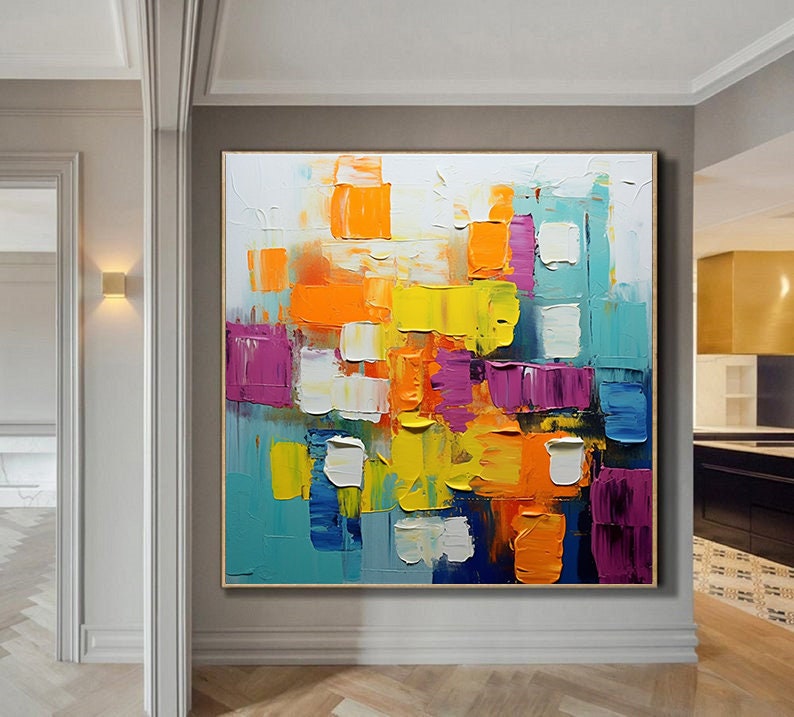 May include: Abstract painting with bold, colorful blocks of yellow, orange, purple, blue, and white paint. The painting has a textured, brushstroke effect.