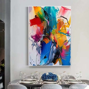 Puede incluir: Pintura abstracta con trazos audaces de amarillo, azul, rojo, verde y rosa. La pintura est&aacute; enmarcada y colgada en una pared blanca.