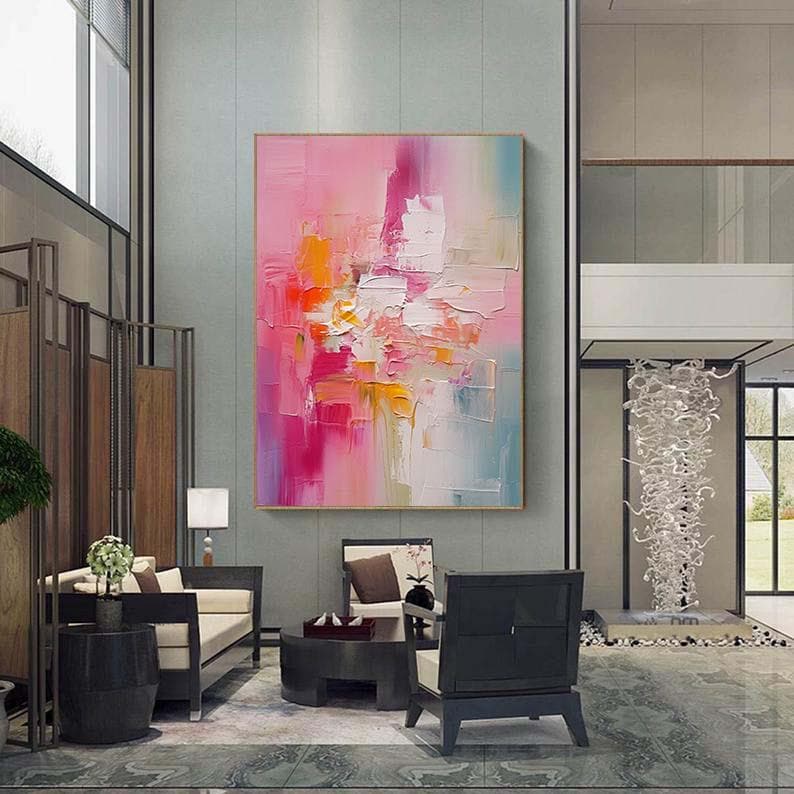 K&ouml;nnte beinhalten: Gro&szlig;es abstraktes Gem&auml;lde mit goldenem Rahmen. Das Kunstwerk zeigt eine lebendige Mischung aus Farben, darunter Rosa, Orange, Wei&szlig; und Blau, die mit dicken Pinselstrichen aufgetragen wurden. Das Gem&auml;lde wird in einem modernen Wohnzimmer pr&auml;sentiert.