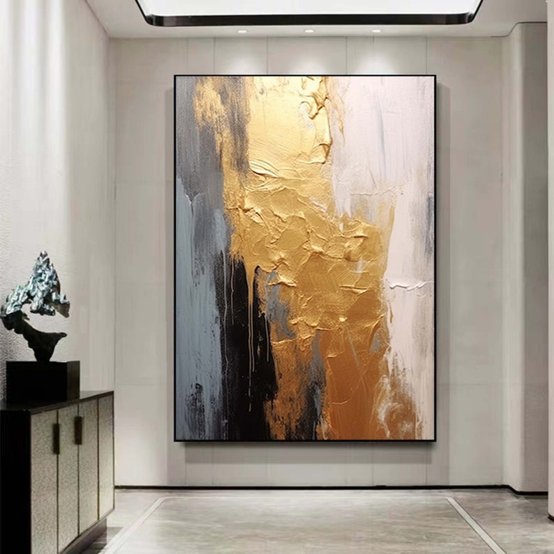 Puede incluir: Pintura abstracta con pinceladas doradas, blancas y grises sobre un fondo negro.