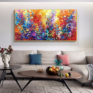 May include: Abstract painting with a colorful, textured, and impressionistic style. The painting features a variety of colors, including red, orange, yellow, green, blue, purple, and white. The painting is framed in a gold frame and is hanging on a white wall above a couch.