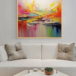 May include: Abstract painting with a colorful, layered design. The painting features shades of pink, yellow, orange, blue, and green. The painting is framed in a light wood frame.