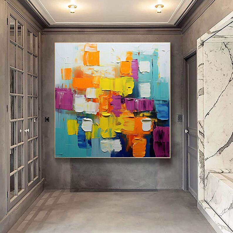 May include: Abstract painting with bold, colorful blocks of yellow, orange, blue, pink, and white paint. The painting has a textured, layered look, with thick brushstrokes and a variety of colors.