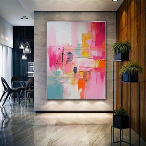 K&ouml;nnte beinhalten: Gro&szlig;es abstraktes Gem&auml;lde mit einer Farbpalette aus Rosa, Orange, Gelb und Blau. Das Kunstwerk weist dicke Pinselstriche und eine strukturierte Oberfl&auml;che auf, die eine moderne und lebendige &Auml;sthetik erzeugt. Das Gem&auml;lde wird in einem zeitgen&ouml;ssischen Innenraum gezeigt.